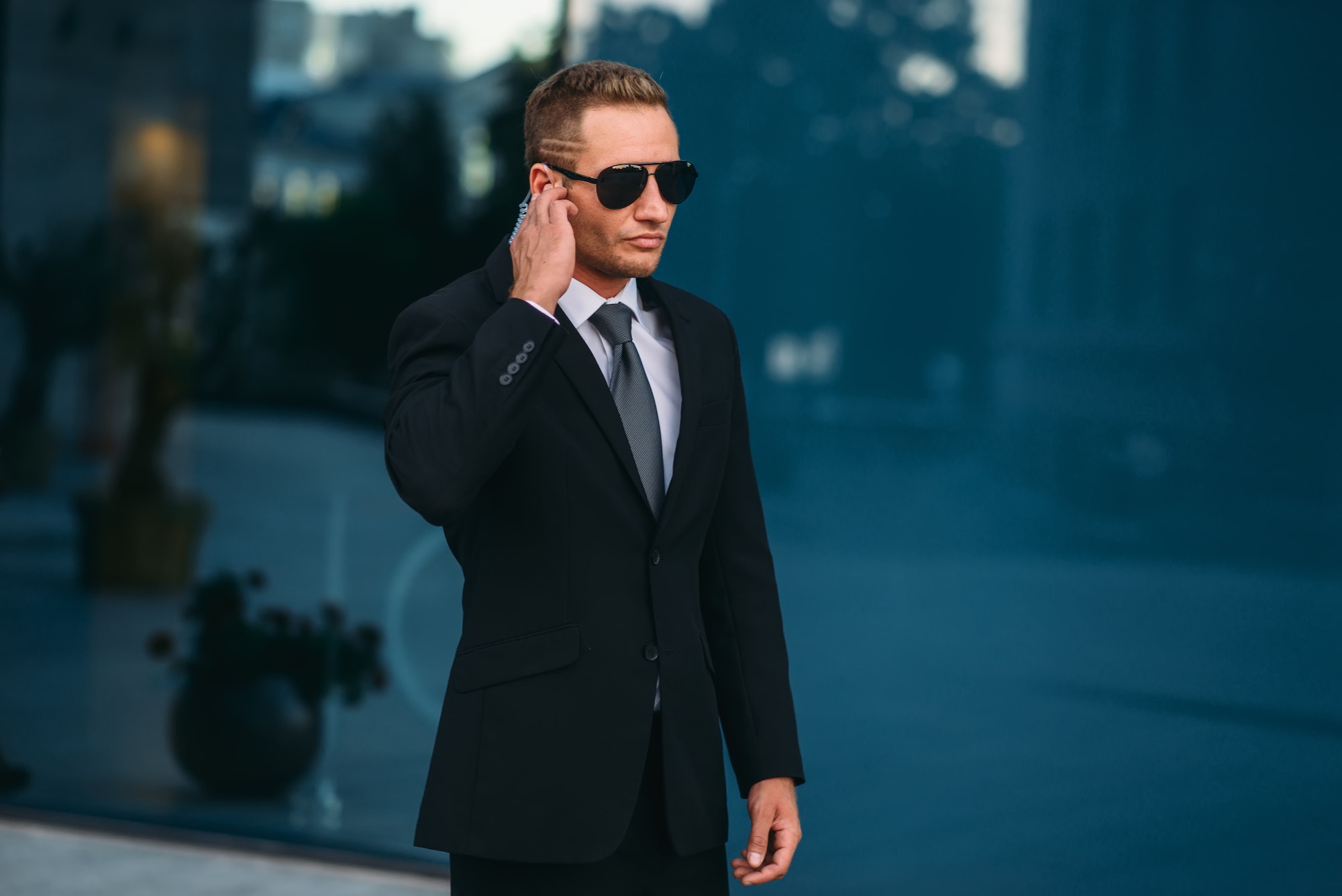 Male bodyguard uses security earpiece outdoors